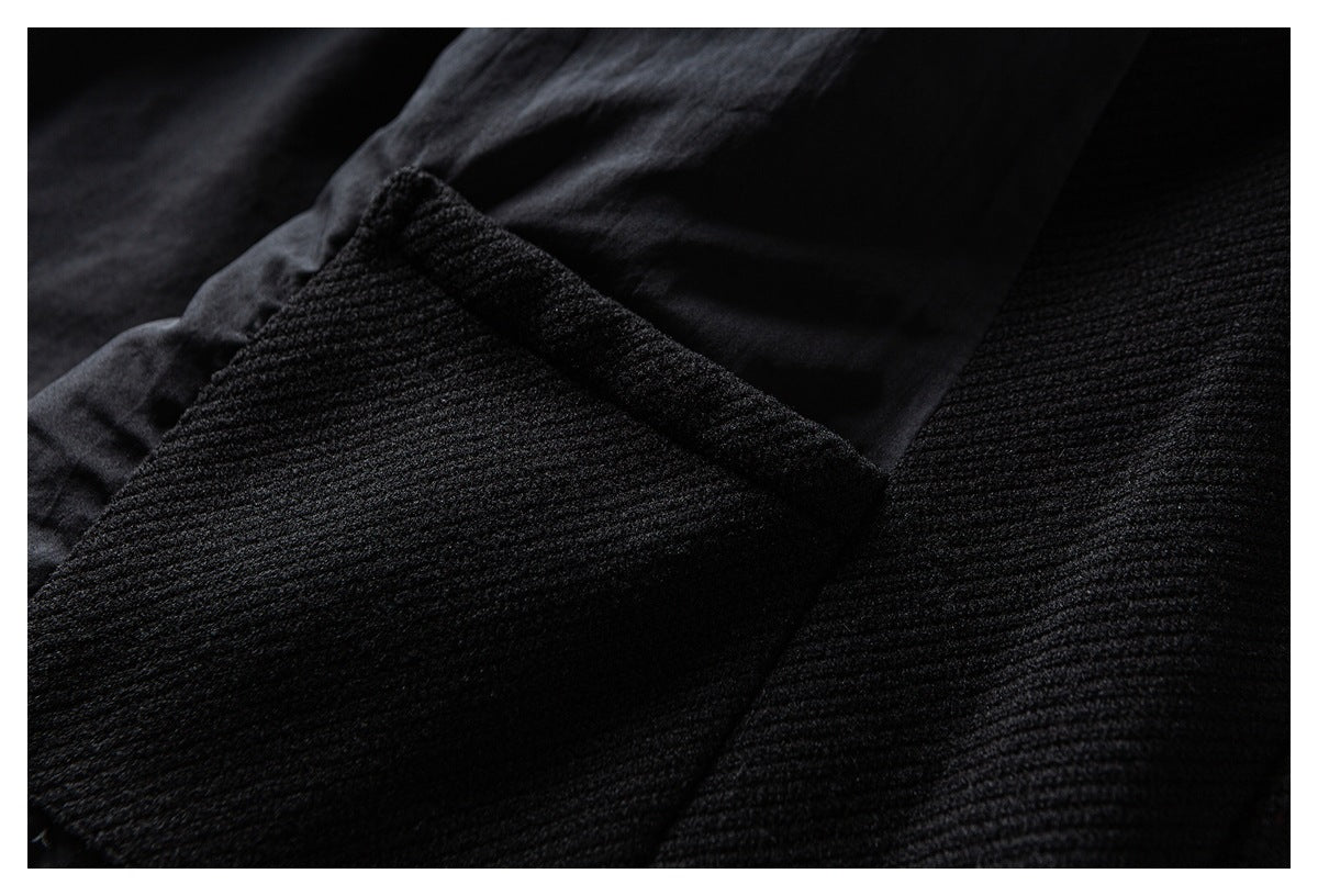 Close-up of a black garment panel showing textured fabric and a stitched edge.