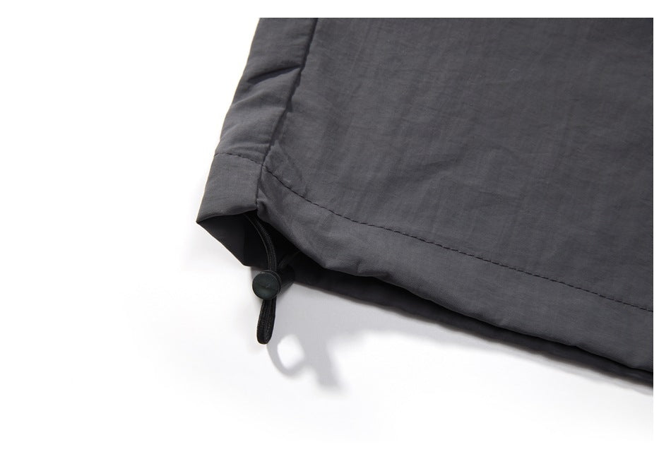 Close-up of a dark charcoal pant hem with an adjustable drawcord and toggle.