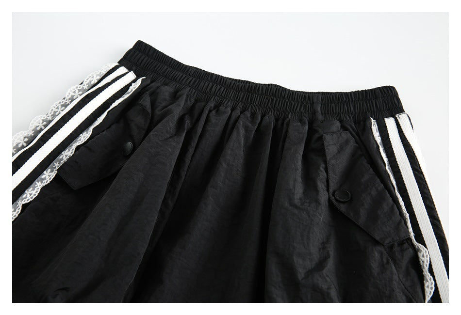 Close-up of the black skirt's elastic waistband and buttoned pockets, with white striped lace trim at the sides.
