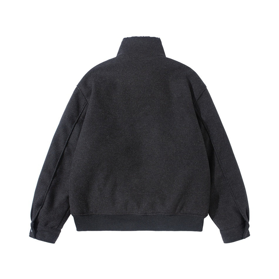 Back view of a dark charcoal jacket laid flat, with a stand collar, long sleeves, and ribbed hem.
