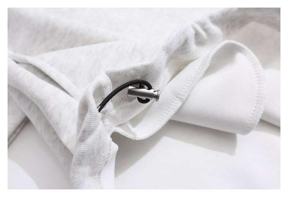 Close-up of a black cord and metal toggle at the edge of a light gray heathered garment.