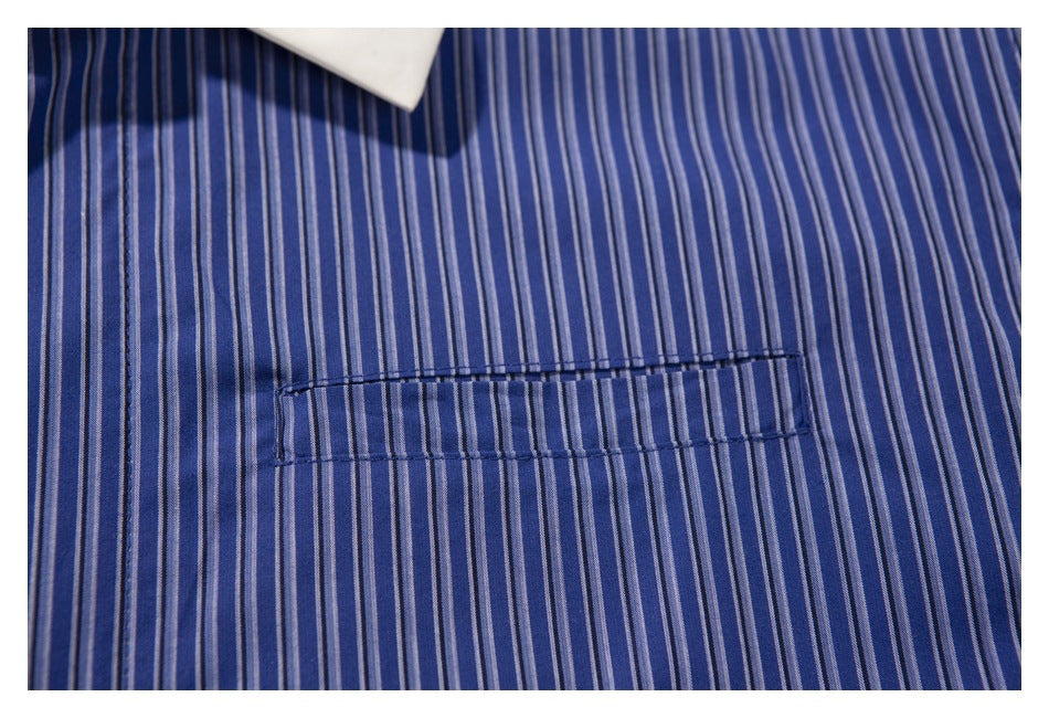 Close-up of the stitched chest pocket on a blue shirt with narrow vertical stripes.