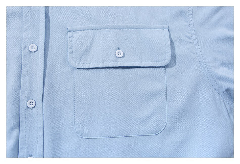 Close-up of a light blue shirt’s buttoned flap chest pocket and front placket.
