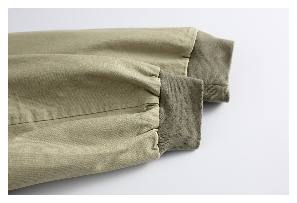 Two beige garment sleeves shown from above, each finished with a dark olive ribbed cuff.