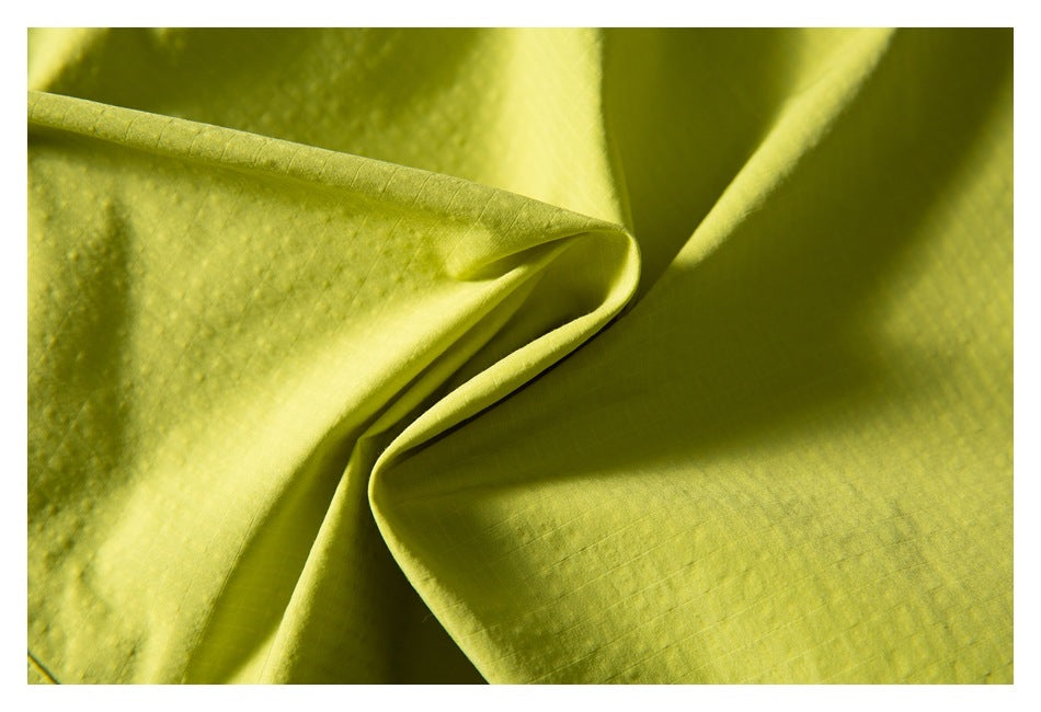 Close-up of lime green fabric folded to show its subtle grid texture.