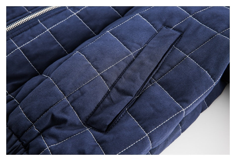 Close-up of a navy quilted garment showing a long welt pocket and light contrast stitching.