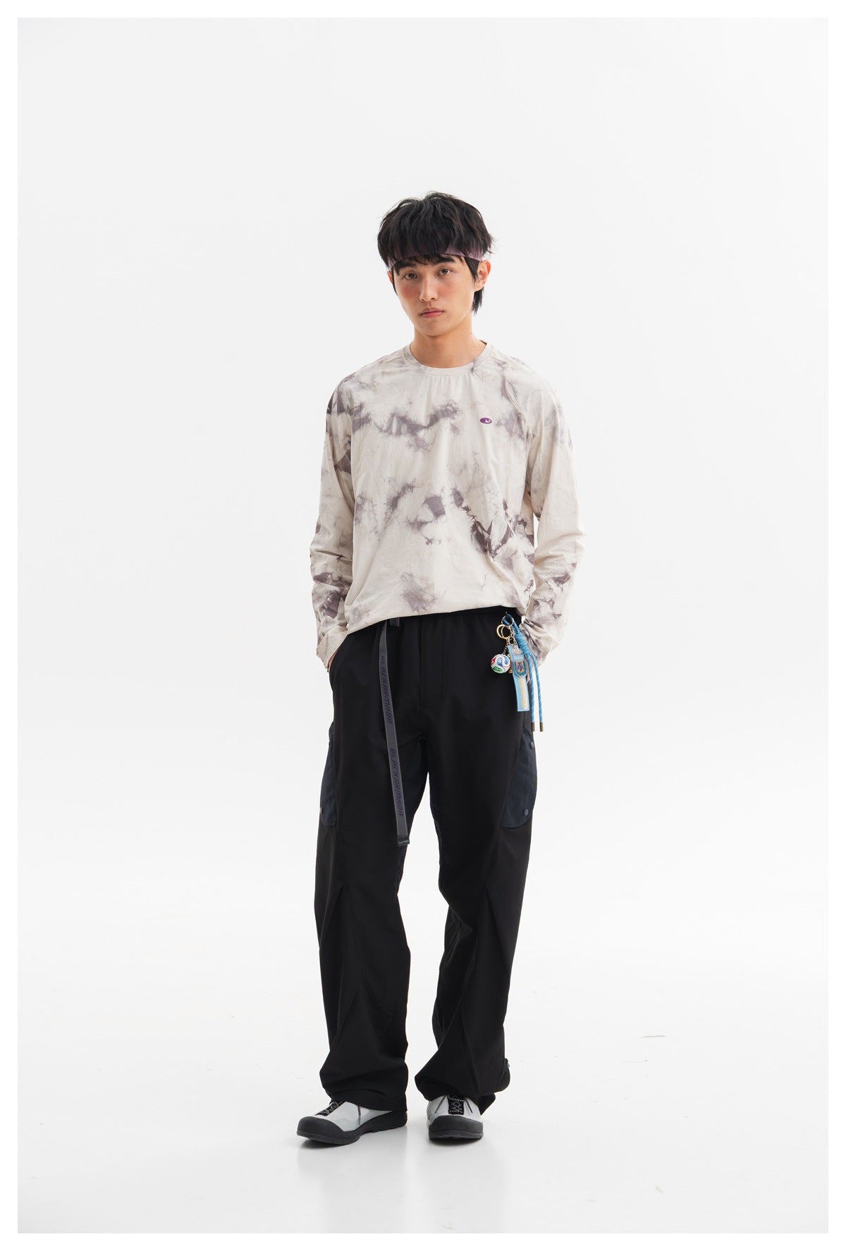 Model wearing a pale gray long-sleeve shirt with muted purple tie-dye accents and black cargo pants.