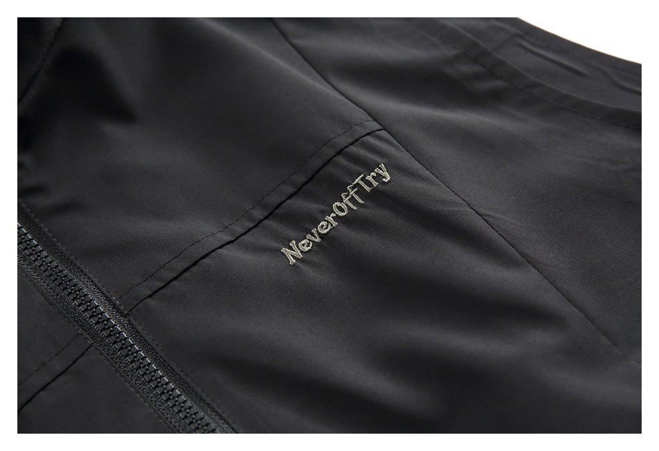 Close-up of the black vest's embroidered chest text and stitching beside the front zipper.