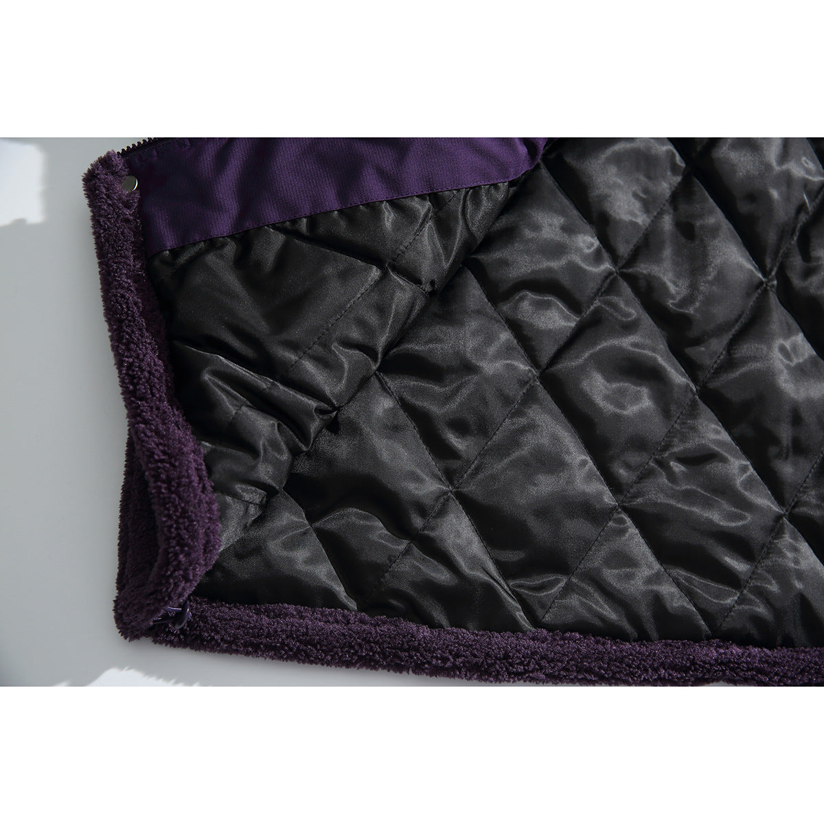 Close-up of the jacket's black diamond-quilted lining bordered by deep purple fleece.