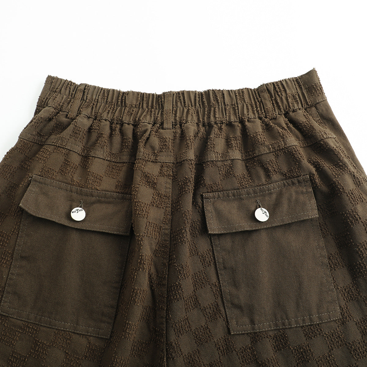 Close-up of the brown checker-textured shorts’ elastic back waistband and two flap pockets.