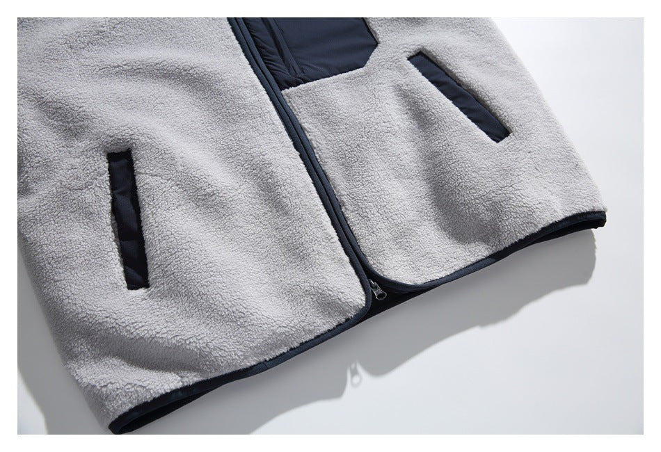Close view of a light gray fleece garment front with a dark zipper, two dark-trimmed pockets, and dark edging.