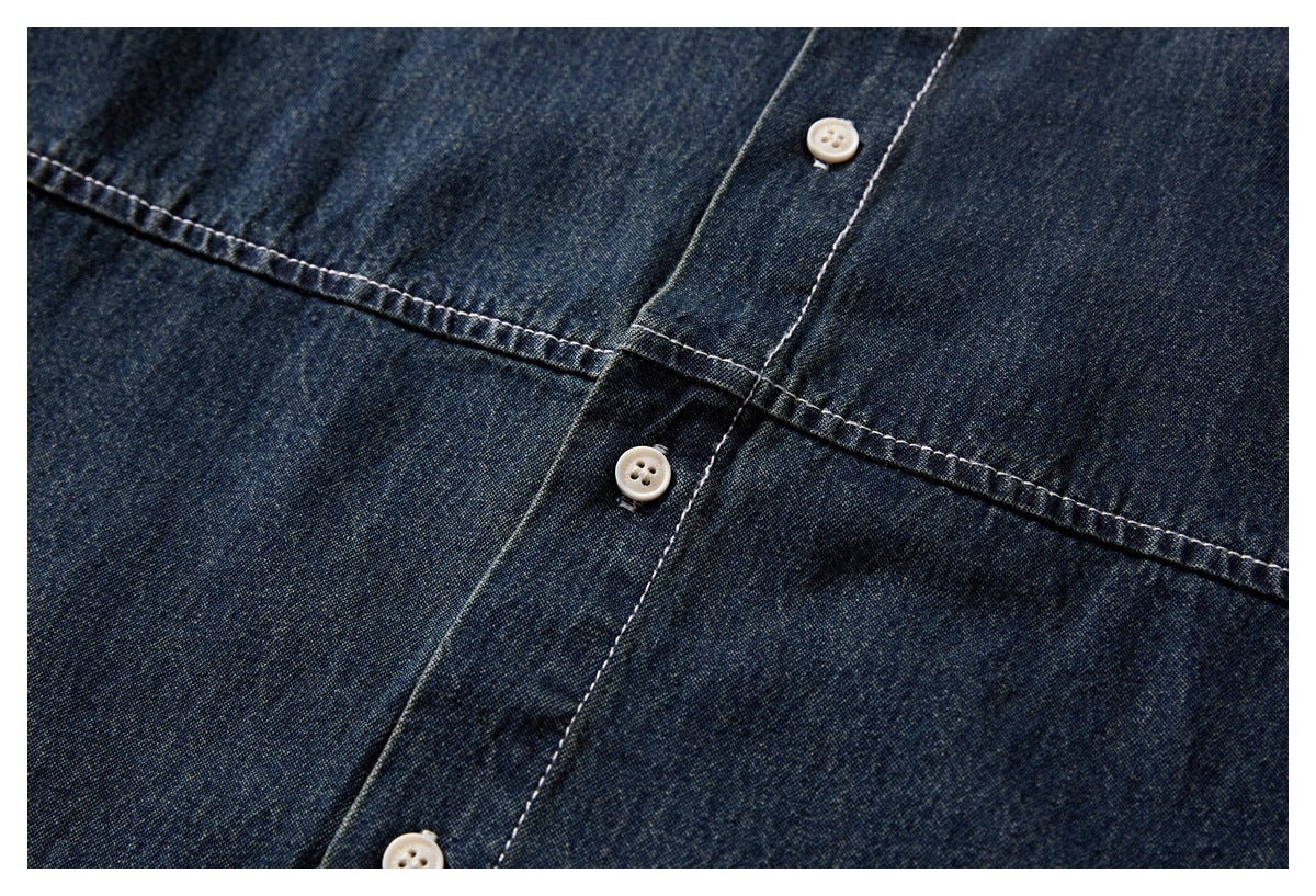 Close-up of dark indigo denim shirt seams and button placket with several white buttons.