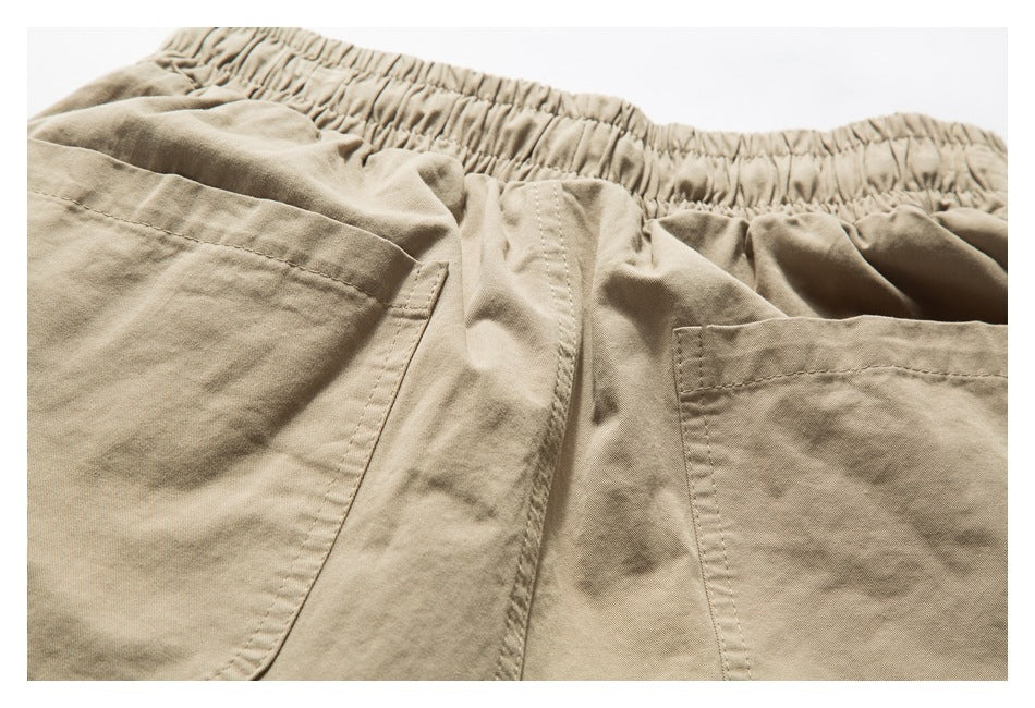 Close-up of beige shorts showing the gathered waistband, center seam, and two pockets.
