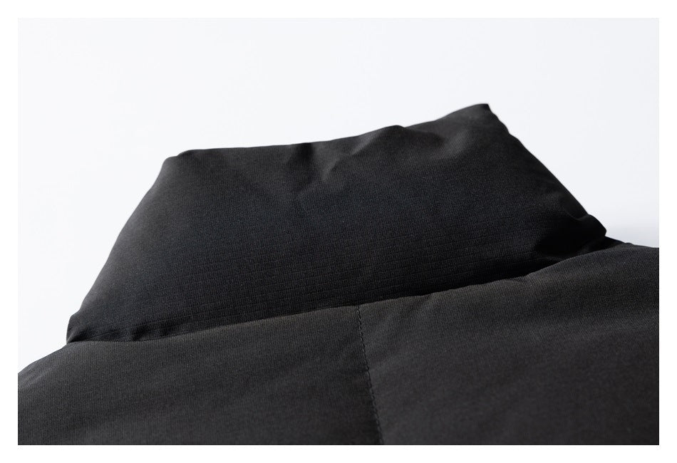Close-up of a black high collar and upper section of a garment against a pale background.