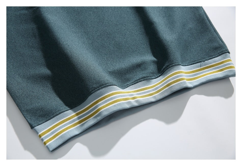Close-up of dark teal fabric with a light blue ribbed hem and mustard and white stripes.