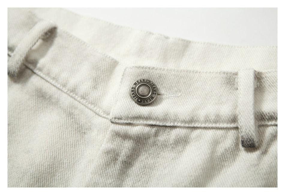 Close-up of the metal waistband button and belt loop on gray-mottled off-white pants.