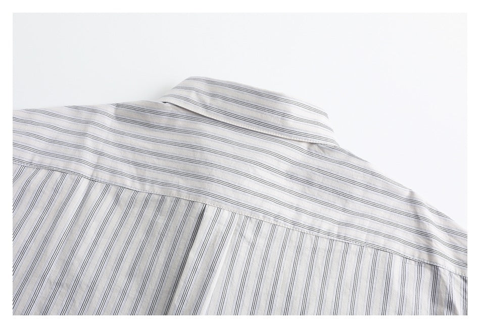 Close-up of a white shirt's back yoke and collar with thin gray stripes.