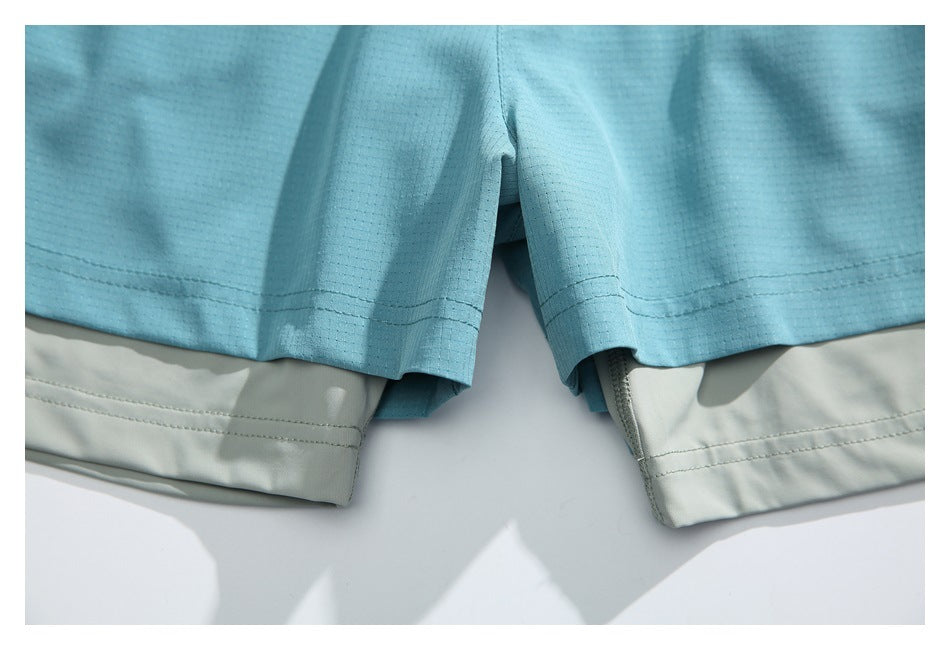 Close-up of the leg openings and crotch area of aqua shorts layered over pale gray inner shorts.