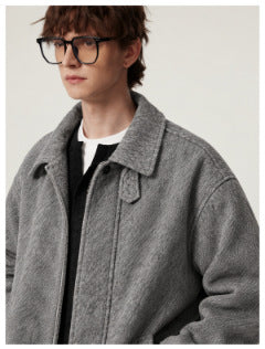 Man wearing gray textured jacket with spread collar over a black and white layered top, close crop