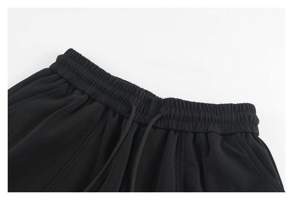 Close-up of black shorts showing the gathered elastic waistband and black drawcords.