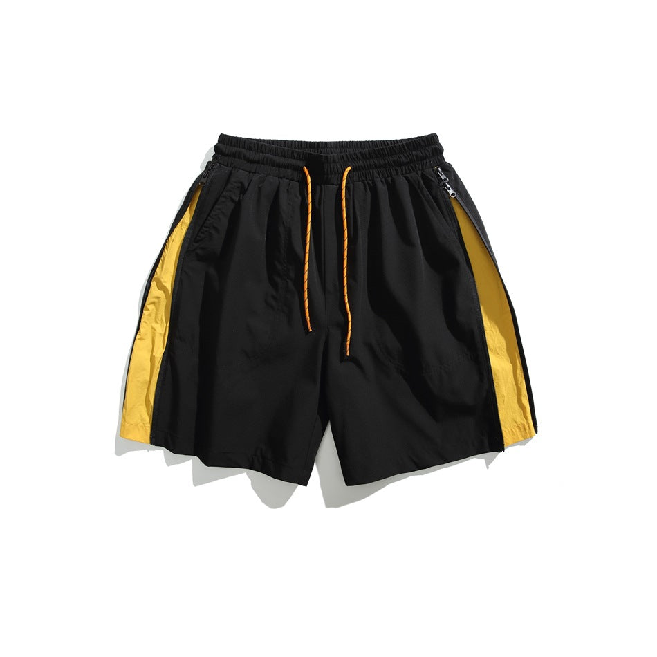 Black shorts with yellow side panels, orange drawcord and zippered side pockets, flat lay