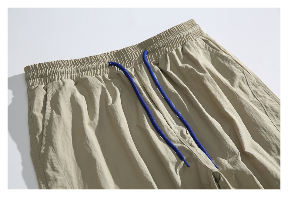 Close-up of beige jogger pants showing the gathered elastic waistband and long blue drawstrings.