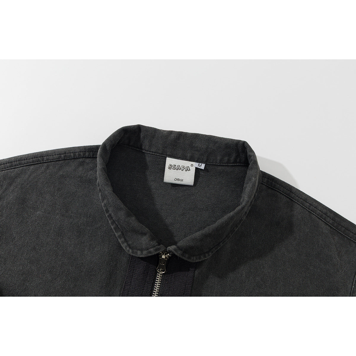 Close-up of a charcoal sleeveless vest collar, front zipper, and inner neck label.