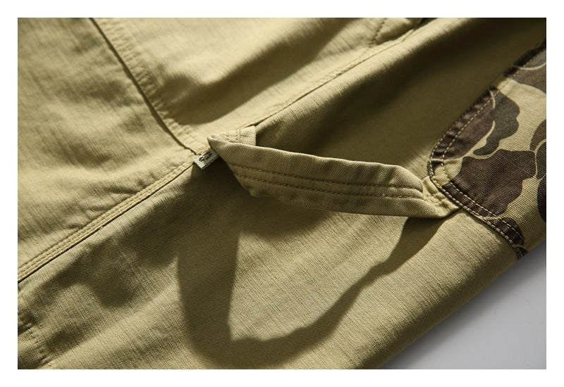 Close-up of a khaki garment with a stitched pocket flap and camouflage-print panel.