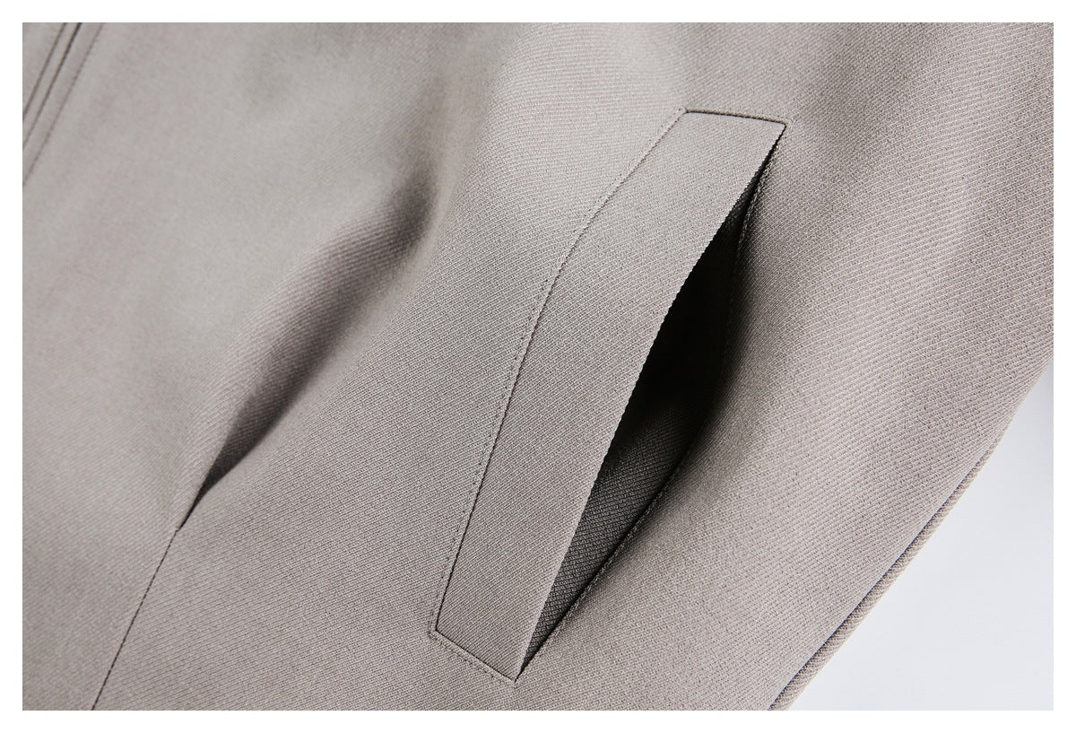 Close-up of an open welt pocket on taupe jacket fabric.