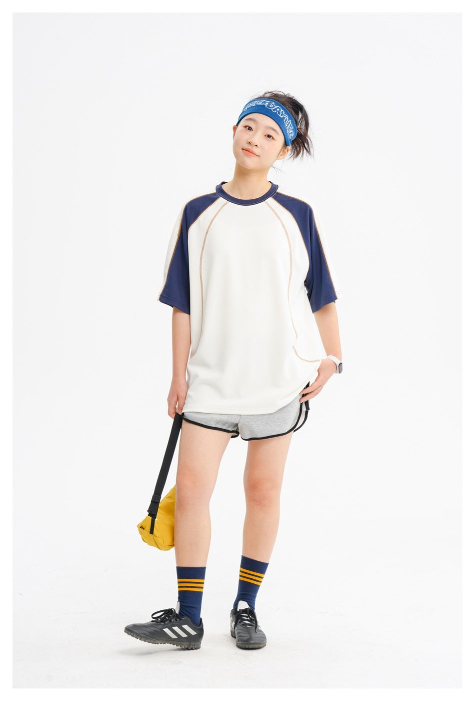 Model wears an oversized ivory raglan T-shirt with navy sleeves and curved contrast stitching.