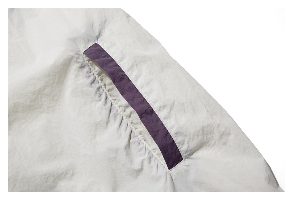 Close-up of an off-white garment panel with a narrow plum-colored inset along a seam.
