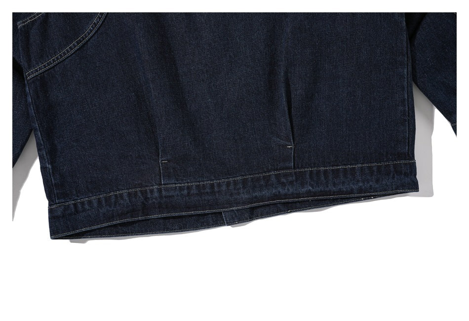 Close-up of the lower back hem and seams of a dark indigo denim jacket.