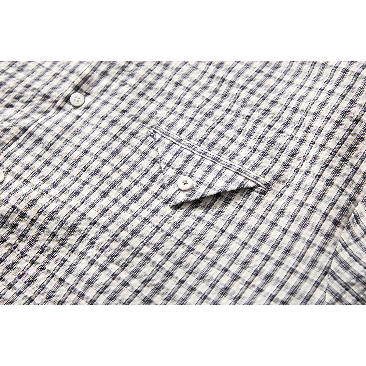 Close-up of a black-and-white plaid shirt’s buttoned chest pocket.