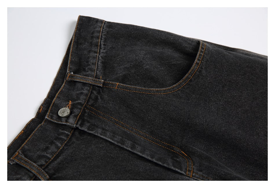 Close-up of black jeans showing the waistband, metal button, belt loop, and curved front pocket.
