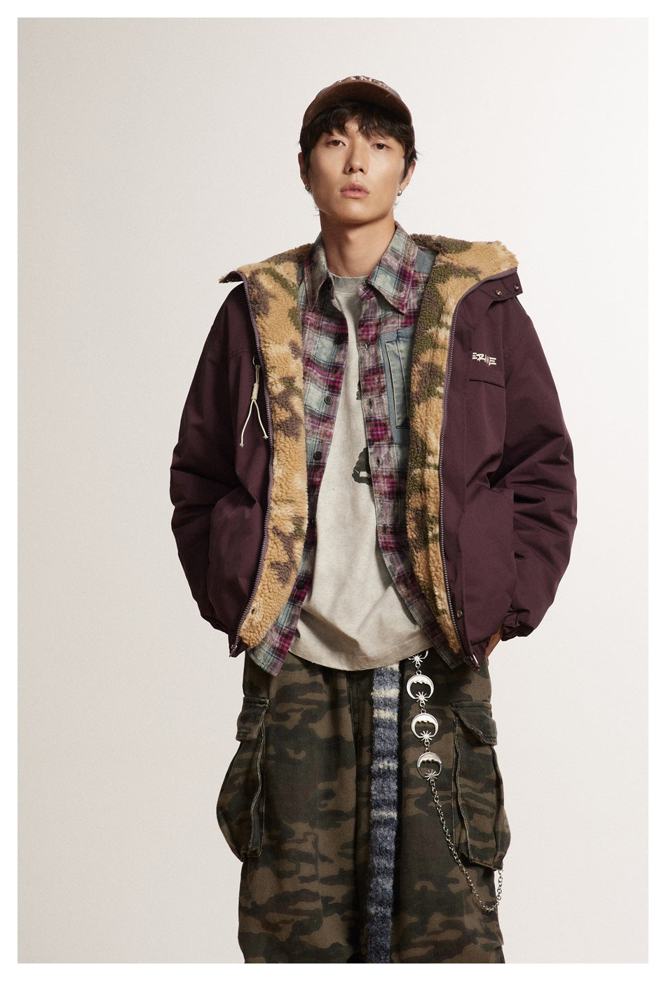 Close view of a model in the burgundy jacket open to show the camouflage fleece-like side, over a plaid shirt