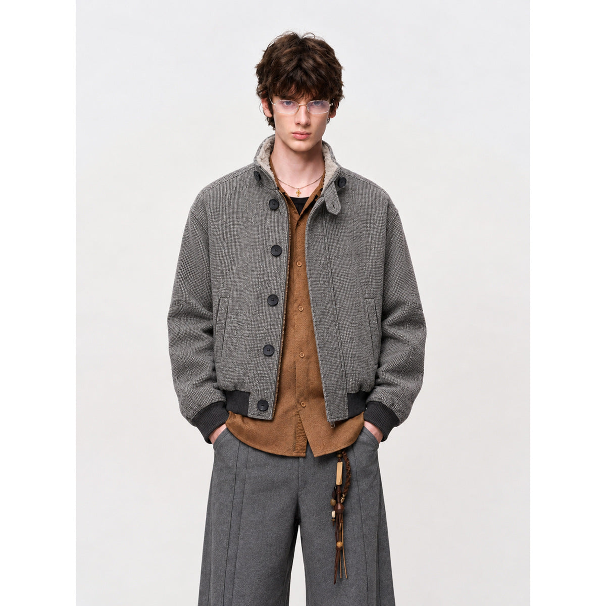 Model wearing a gray patterned bomber jacket with a button front, dark ribbed cuffs and hem, and a light fleece-lined collar.
