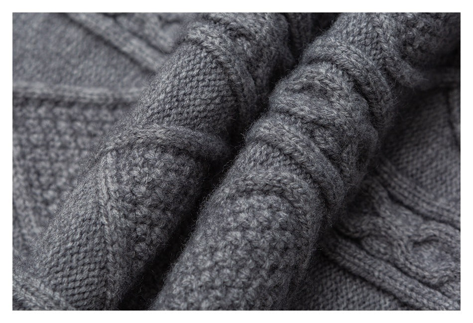 Close-up of folded gray knit showing raised cable stitches and textured panels.