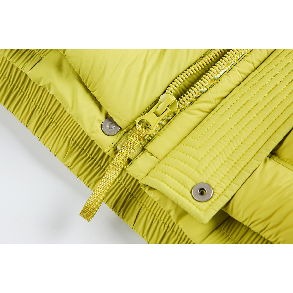 Close-up of a lime padded jacket's zipper, snap fasteners, stitched placket, and gathered hem.