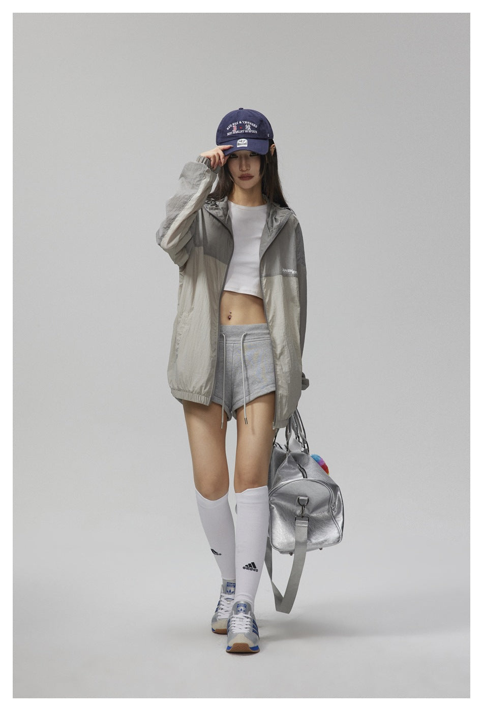 Model wearing an open gray and cream color-block hooded jacket with gray shorts.