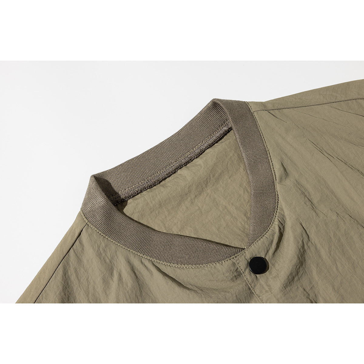 Close-up of an olive-taupe garment neckline with ribbed trim and a black snap button.