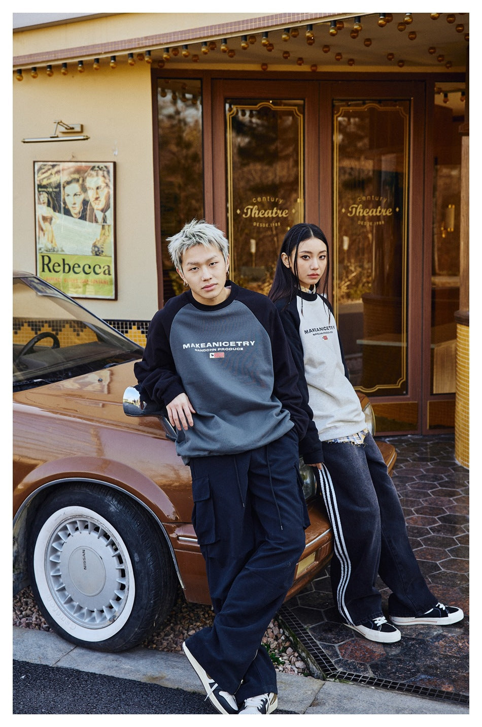 Two models pose by a car in charcoal-and-black and white-and-black raglan sweatshirts with chest lettering.