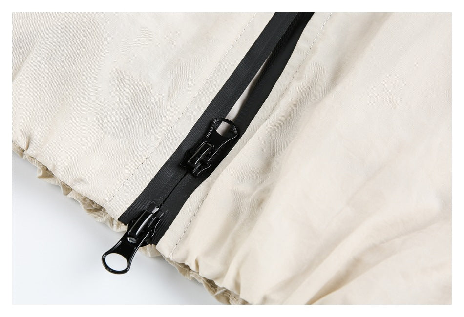 Close-up of a black zipper with two pulls on light beige garment fabric.
