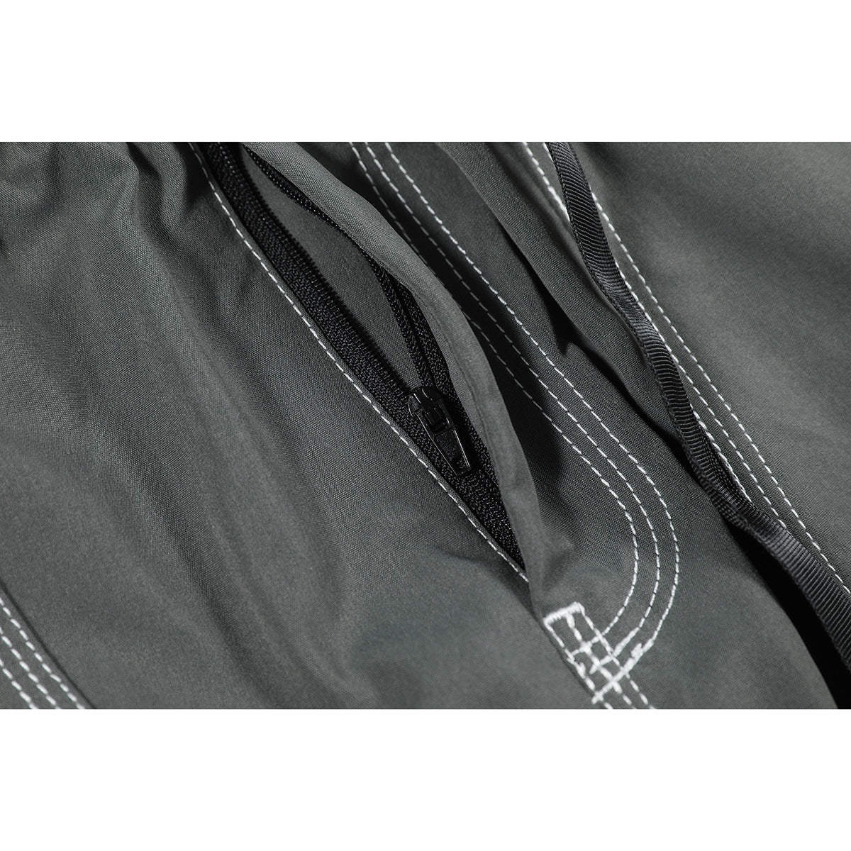 Close-up of a black zippered pocket and white double stitching on charcoal gray pants.