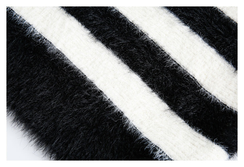 Close-up of fuzzy black knit with broad diagonal ivory stripes and a garment edge.