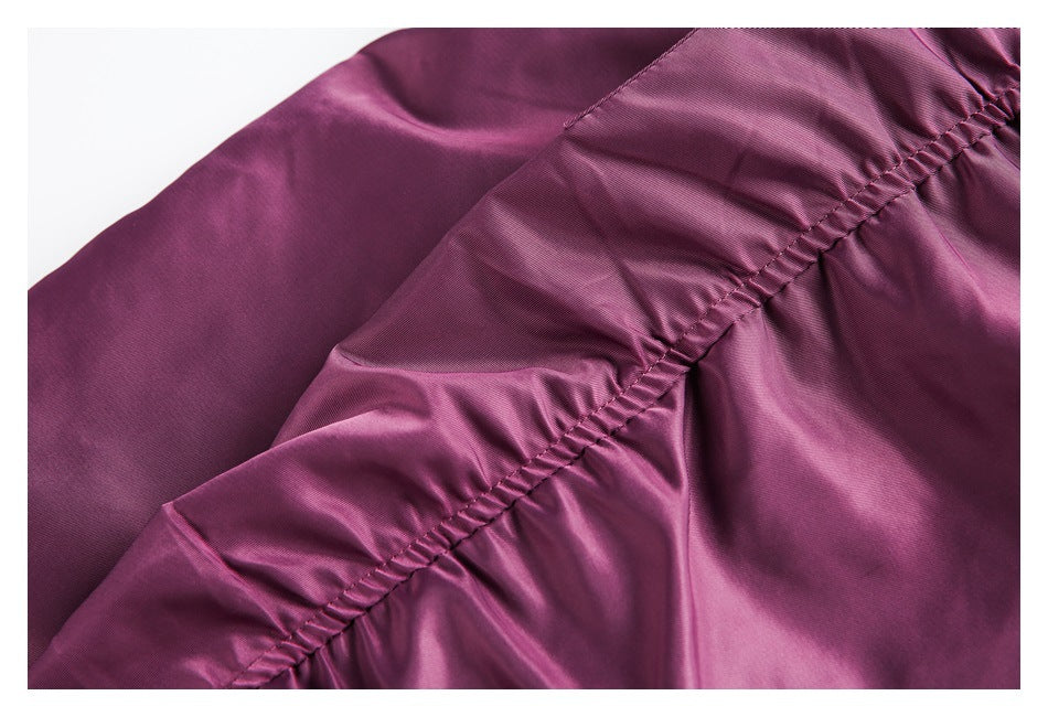 Close-up of gathered stitching along a seam on the plum jacket.