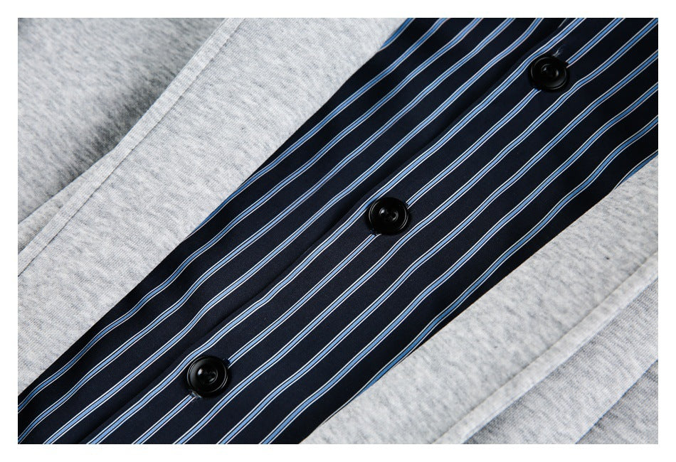 Close-up of a navy placket with thin blue and white stripes and three black buttons, bordered by light gray fabric.