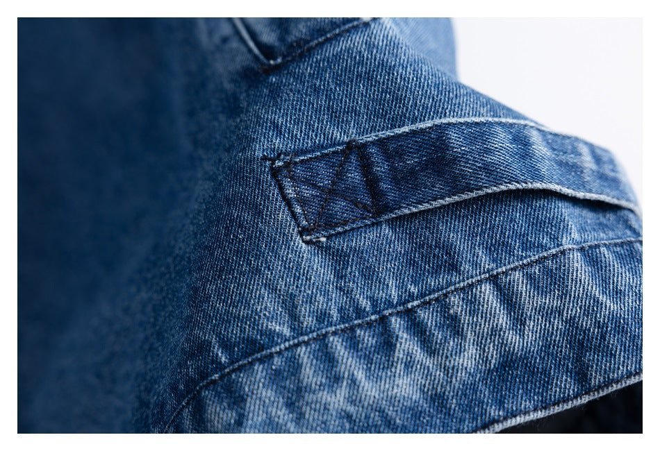 Close-up of a stitched denim tab and intersecting seams on blue fabric.