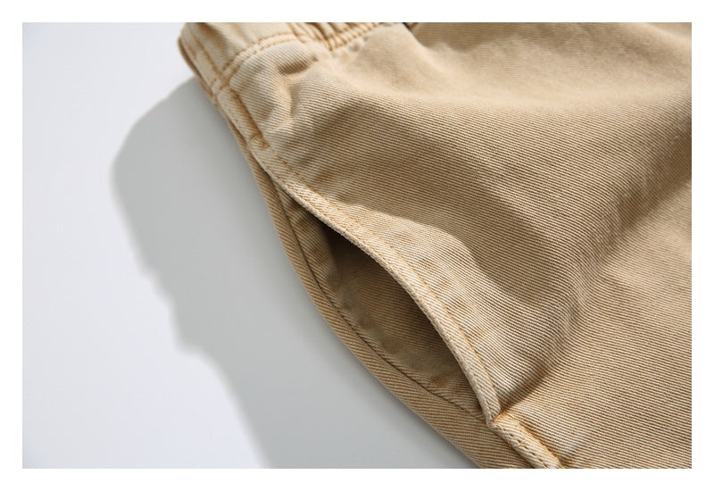 Close-up of the curved side pocket opening and stitching on tan trousers.
