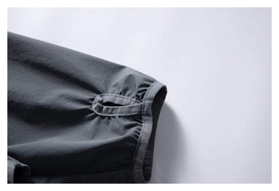 Close-up of a dark gray jacket sleeve cuff with a small fabric loop and stitched edging.