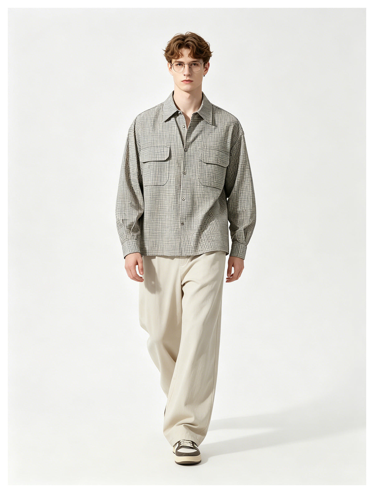 Model wearing a light gray checked button-up shirt with two chest pockets and loose cream trousers.